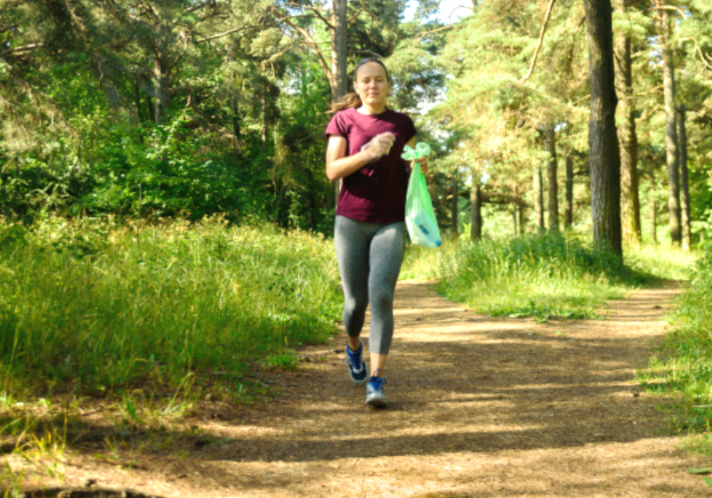 Mulher em local arborizado praticando plogging