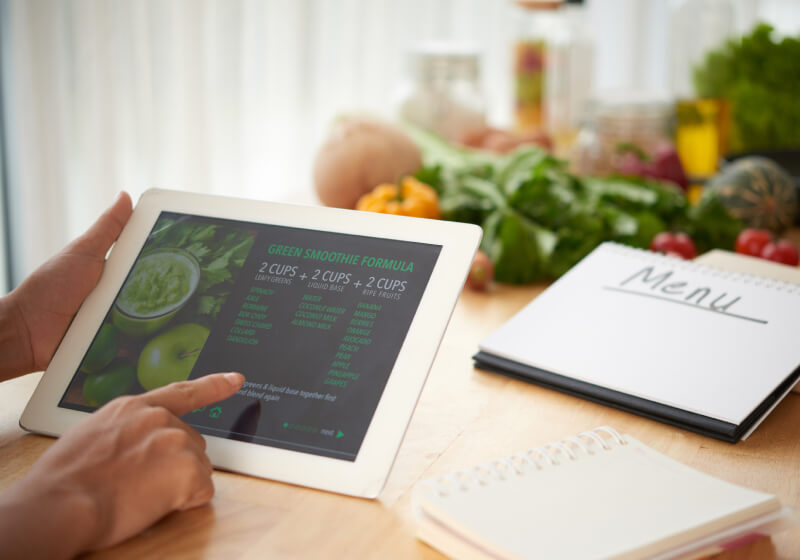 Mão segurando tablet, apresentando receita de dieta