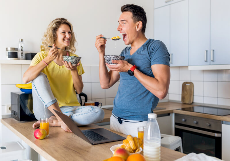 Homem e mulher em cozinha, segurando tigela de comida