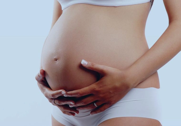 mulher com as mãos apoiadas em sua barriga de grávida