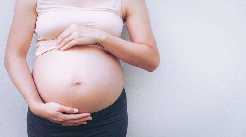 imagem recortada no tronco e com close em uma barriga de grávida 