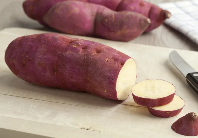 batatas doce roxa em ciam da tabua com uma faca