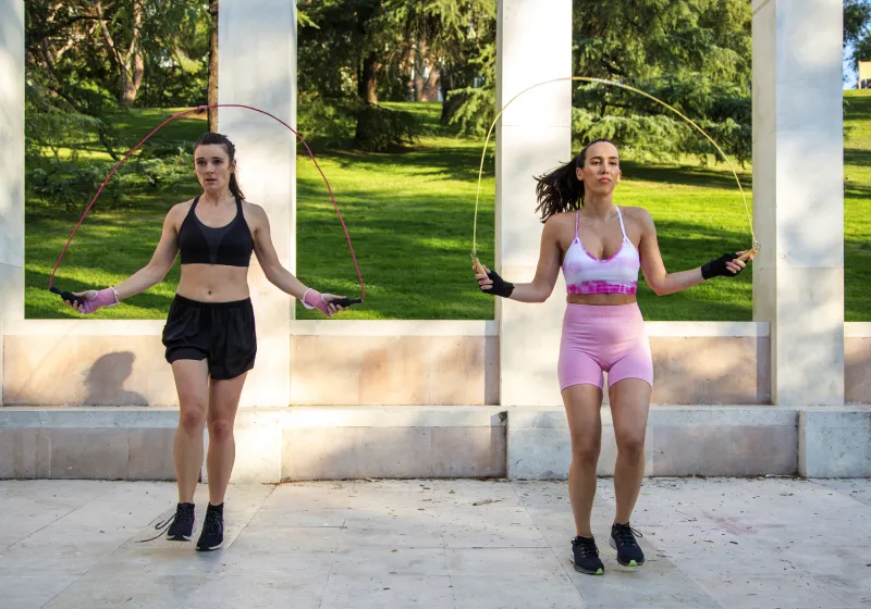 duas mulher fitness pulando corda num parque