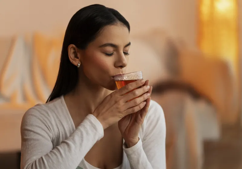 mulher bebendo chá em xicara transparente de vidro 