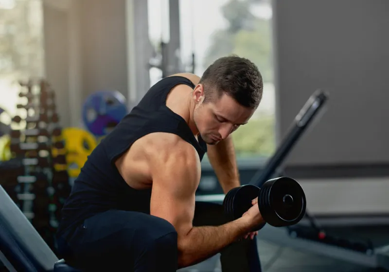 homem desportivo fazendo exercícios para bíceps na academia 
