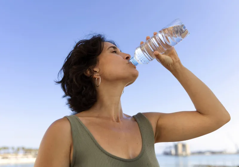 mulher mais velha bebendo água em garrafa em um dia de sol quente 