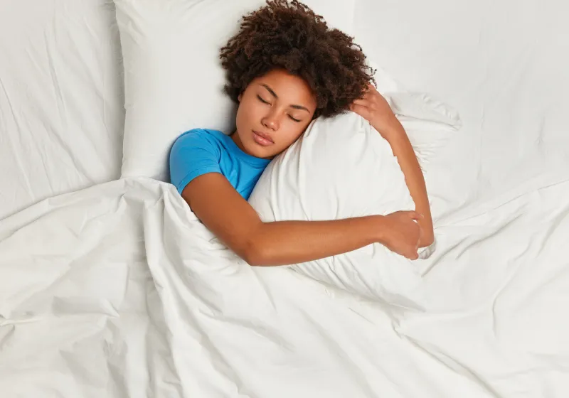 vista superior de mulher negra deitada na cama dormindo 