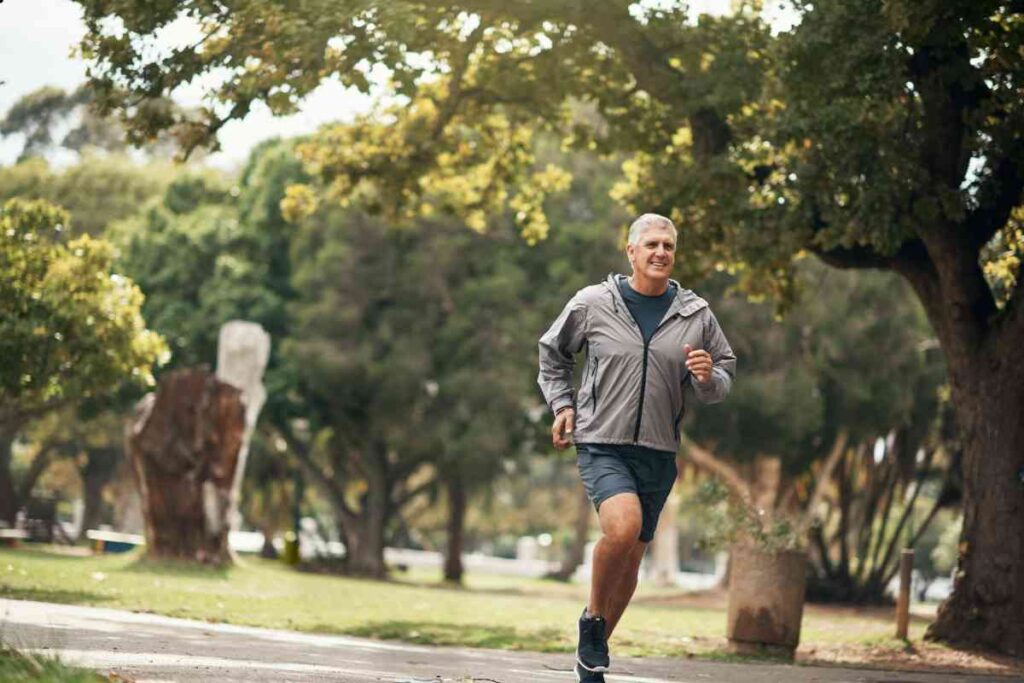 homem com blusa e shorts de corrida correndo em um parque 