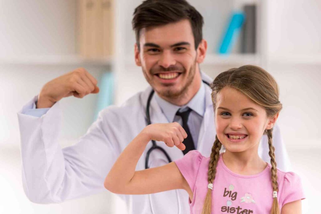 Médico e criança posando para foto flexionando o braço para indicar força