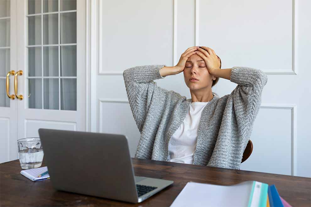 uma mulher com as mãos na cabeça totalmente estressada com o trabalho no escritório de sua casa 