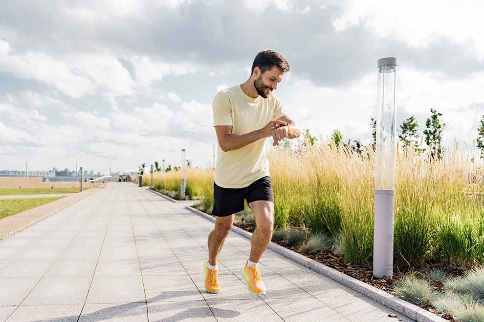 um homem com energia fazendo uma corrida em uma pista de caminhada enquanto olha o relógio no pulso