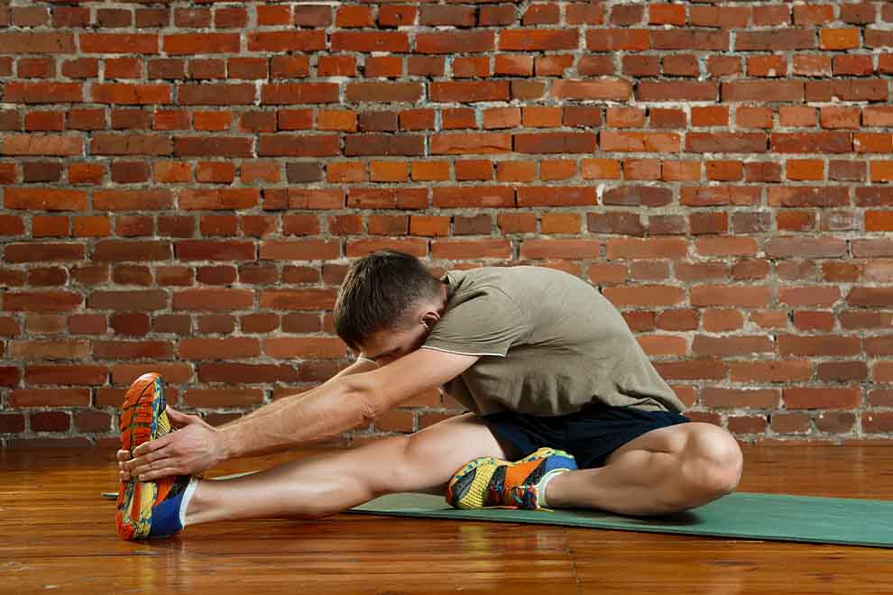 magnésio dimalato Homem se alongando em um tapete de yoga